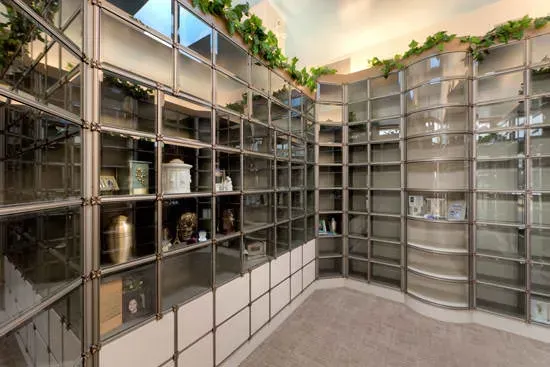 Modern indoor columbarium with glass-front niches and plaques in a bright, curved hallway