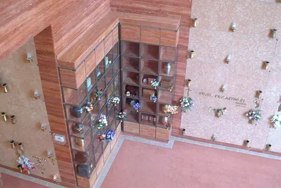Glass display cabinet in a pink room, filled with small figurines and decorative items.
