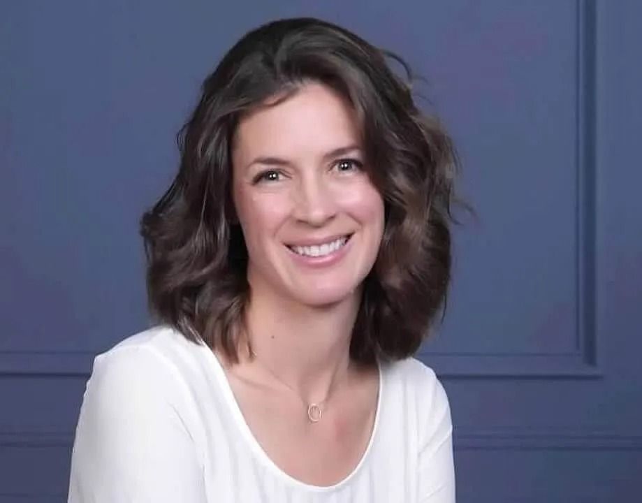 Smiling woman in a white top against a blue studio background