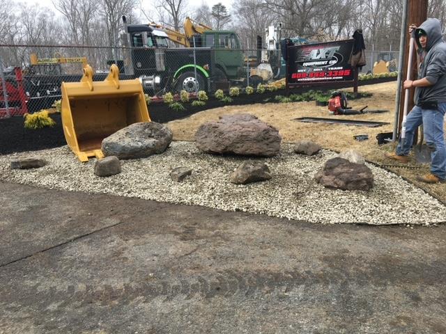 Construction equipment display with rocks, gravel, and a man working outside.