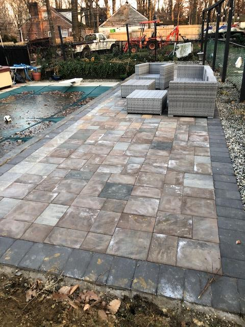 Patio with gray square pavers, a wicker sofa set, and a pool with a blue cover.