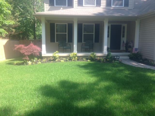 House exterior with green lawn, covered porch, and small garden.