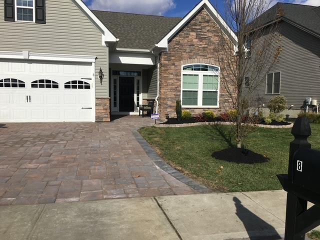 A suburban house with a paved driveway and walkway; a mailbox in the foreground.