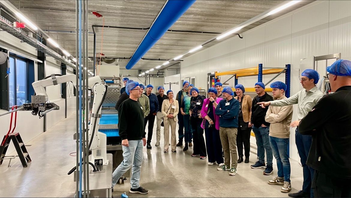 Een groep mensen staat in een kamer in een fabriek.