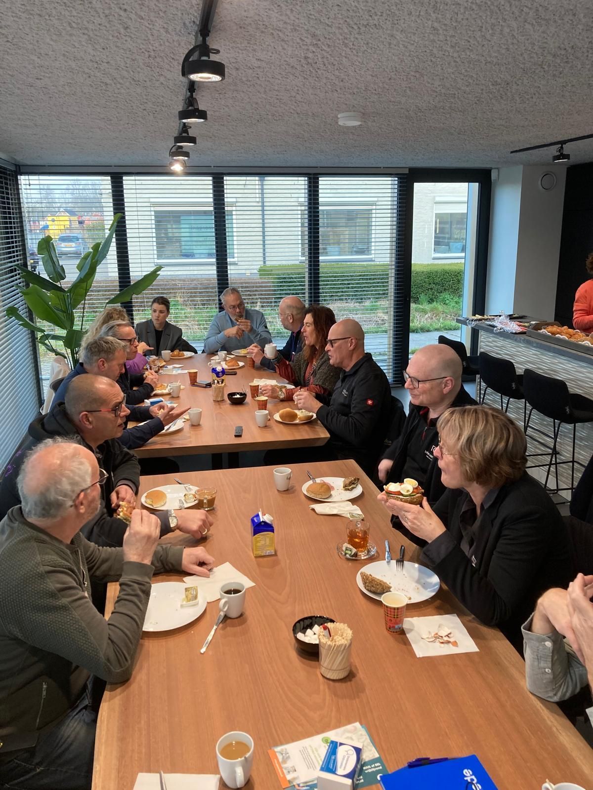 Een groep mensen zit aan een lange tafel te eten.
