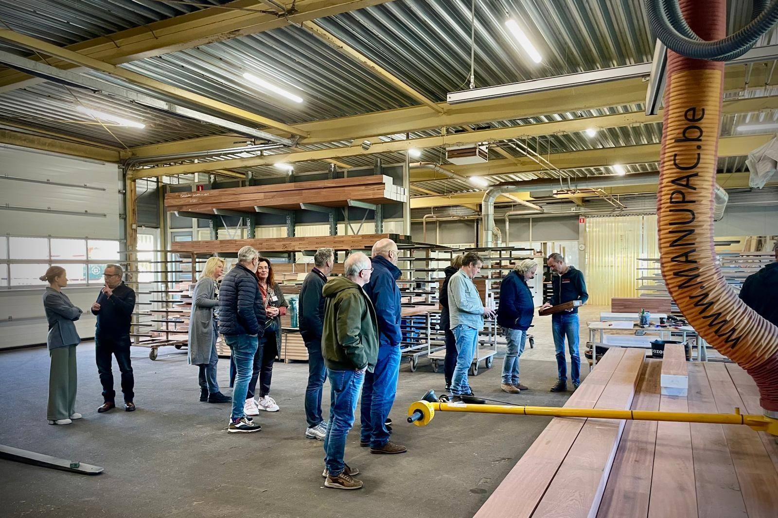 Een groep mensen staat in een pakhuis met elkaar te praten.