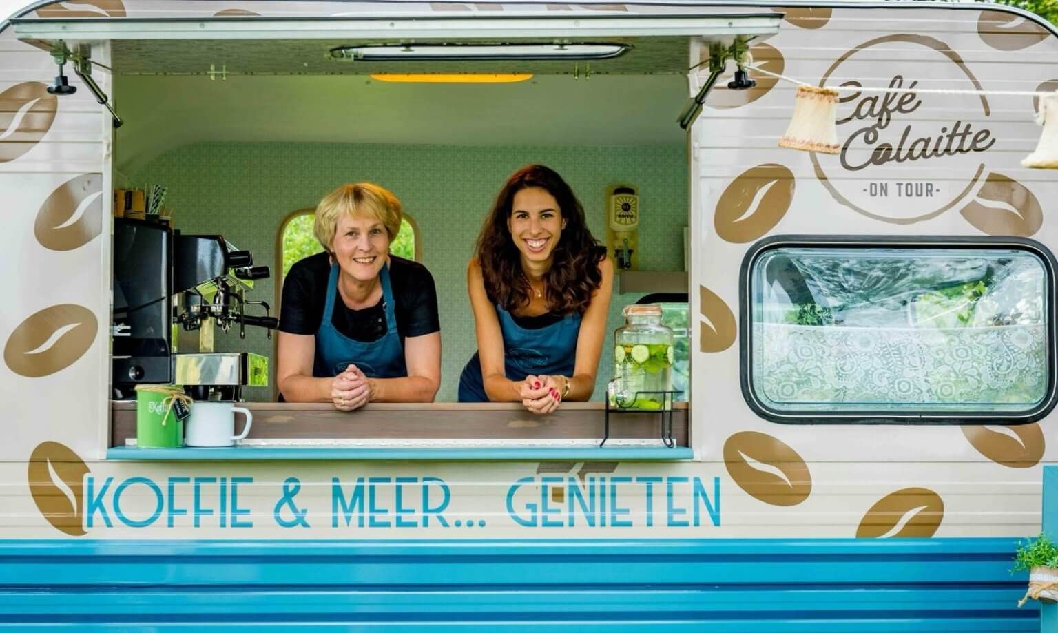Twee vrouwen bij het raam van een blauwe foodtruck, Café Colaitte. Koffie en drankjes verkrijgbaar.