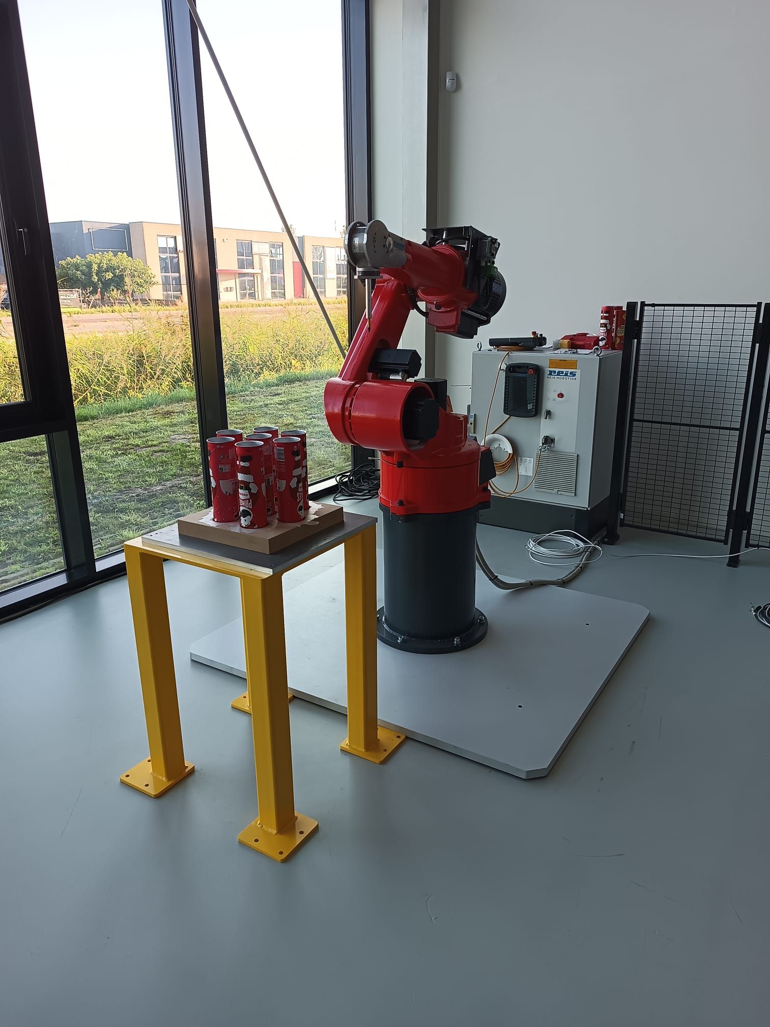 Een rode robot zit op een tafel in een kamer naast een raam.