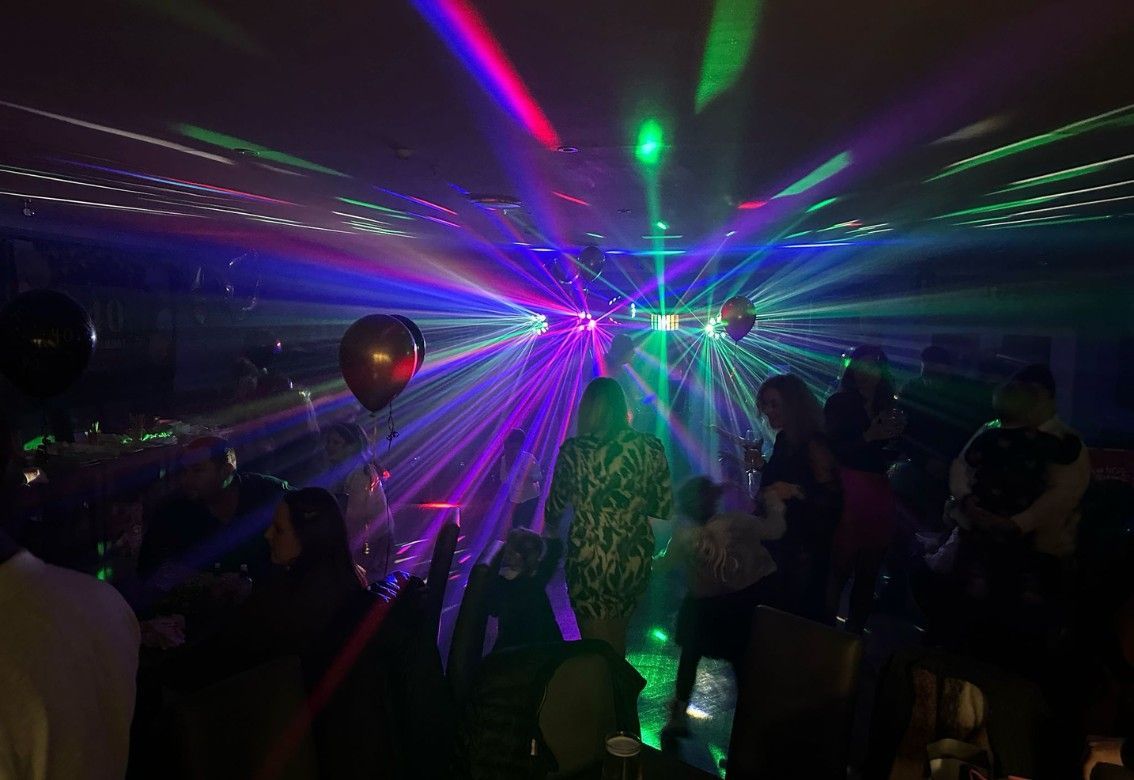 Crowded nightclub with colorful laser beams and dim silhouettes dancing