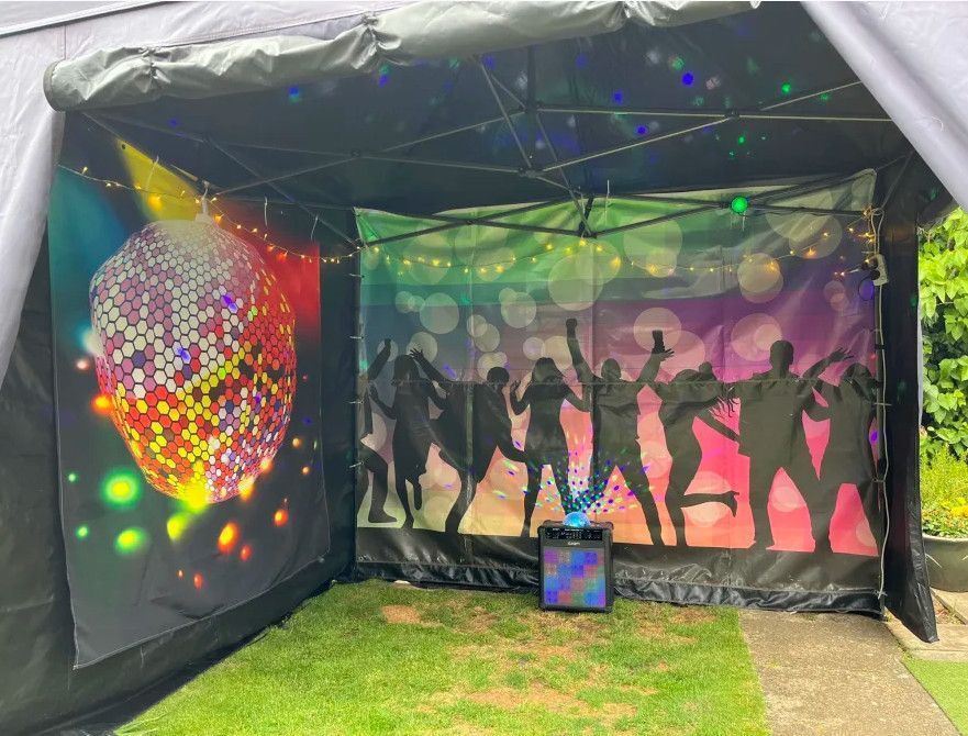 Disco-themed outdoor booth with dancing silhouettes, rainbow lights, and a glittery disco ball display