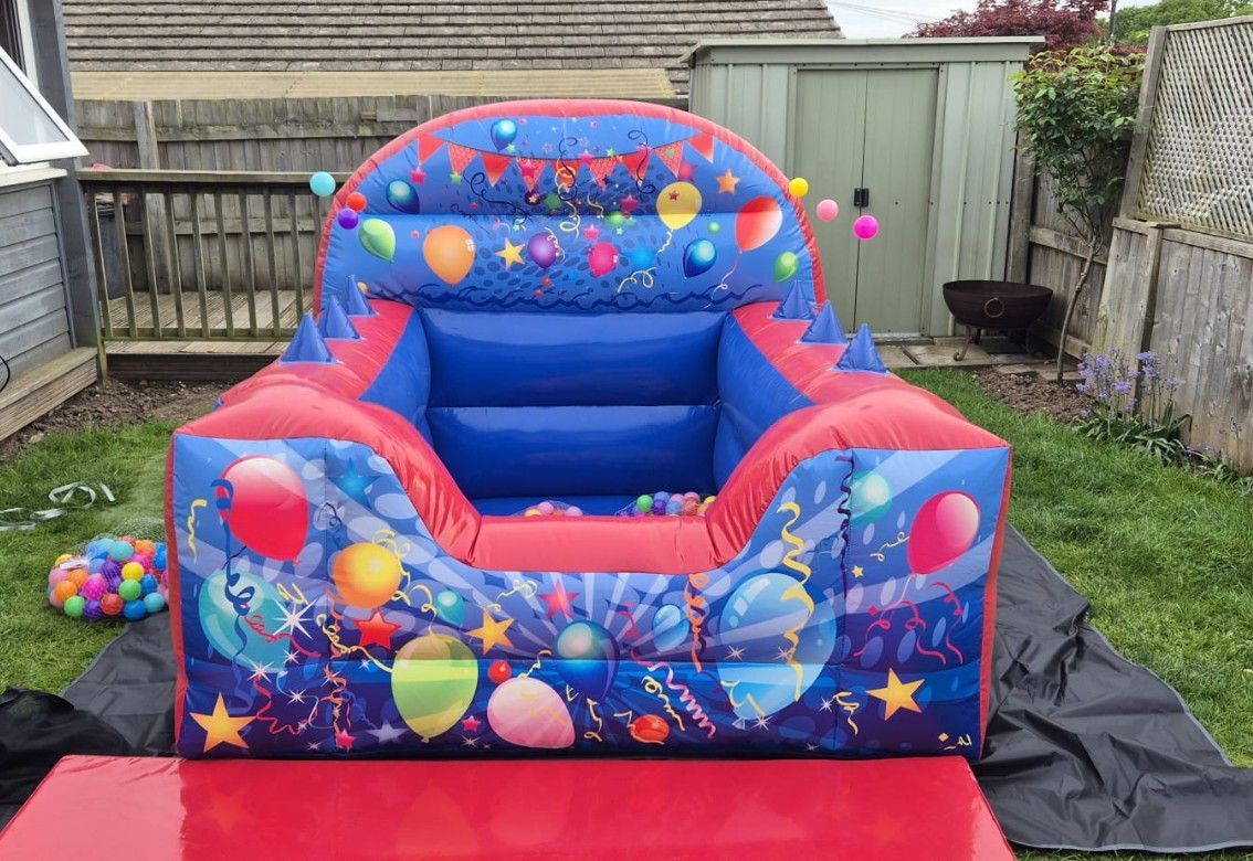Colorful inflatable bounce seat in a backyard, with cartoon space decorations and a red landing mat