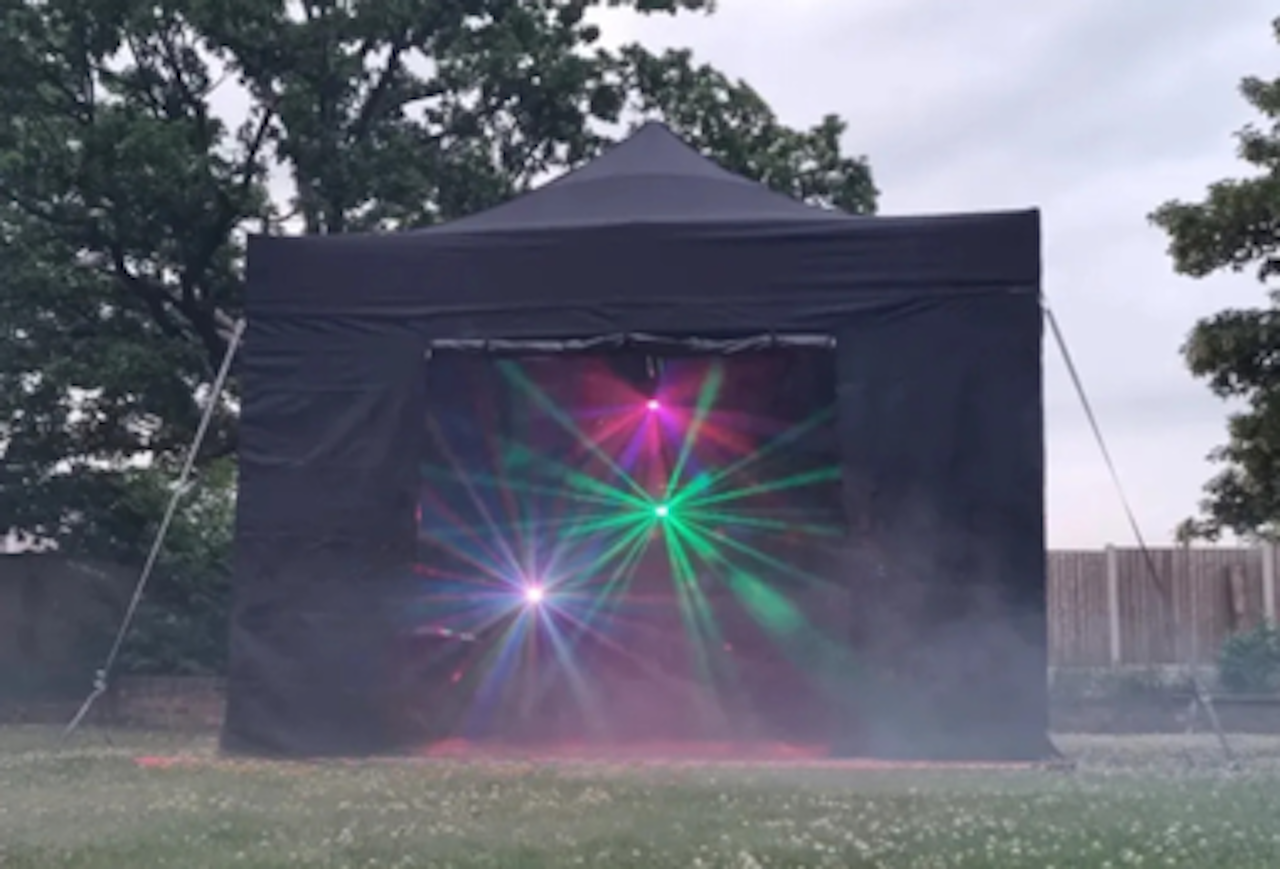 Black outdoor tent with a glowing multicolor starburst light display inside