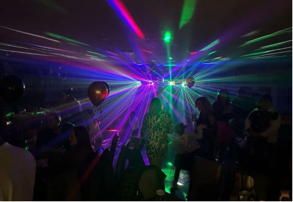 Dim nightclub with colorful laser lights over a dancing crowd