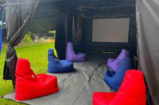 Outdoor tent lounge with colorful bean bags and a projection screen inside