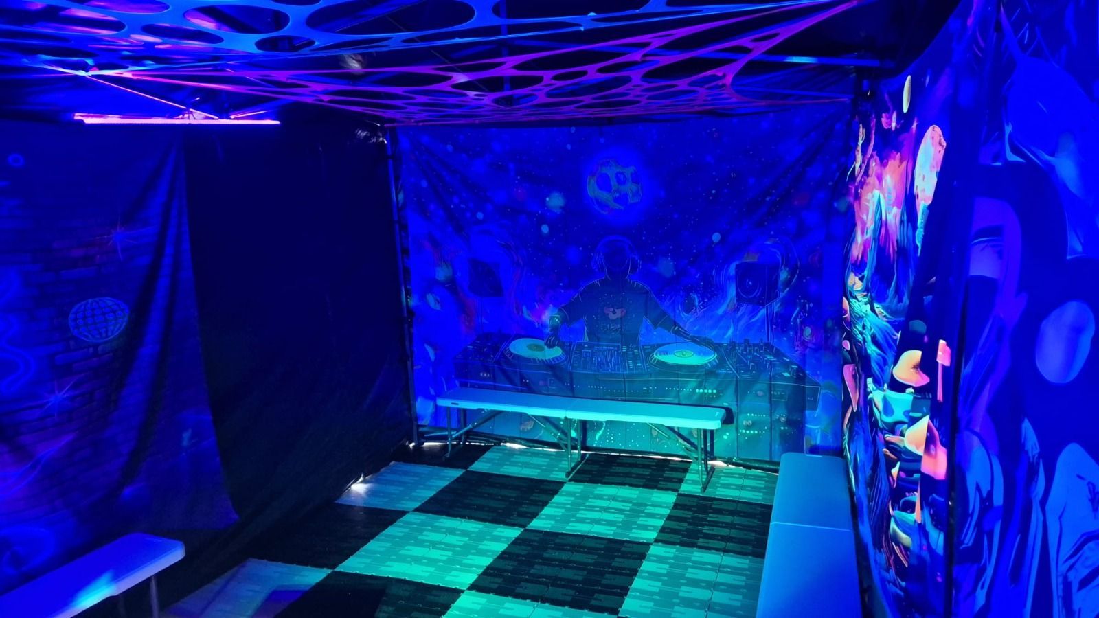 Neon-lit room with blue and purple UV lighting, patterned walls, and a checkered floor tunnel