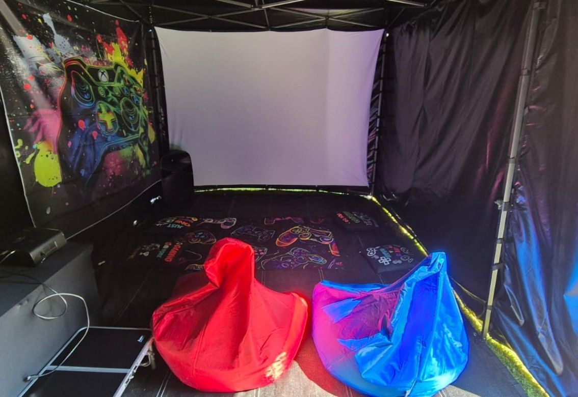 Blacklit lounge with white screen, graffiti wall, and red and blue beanbag chairs