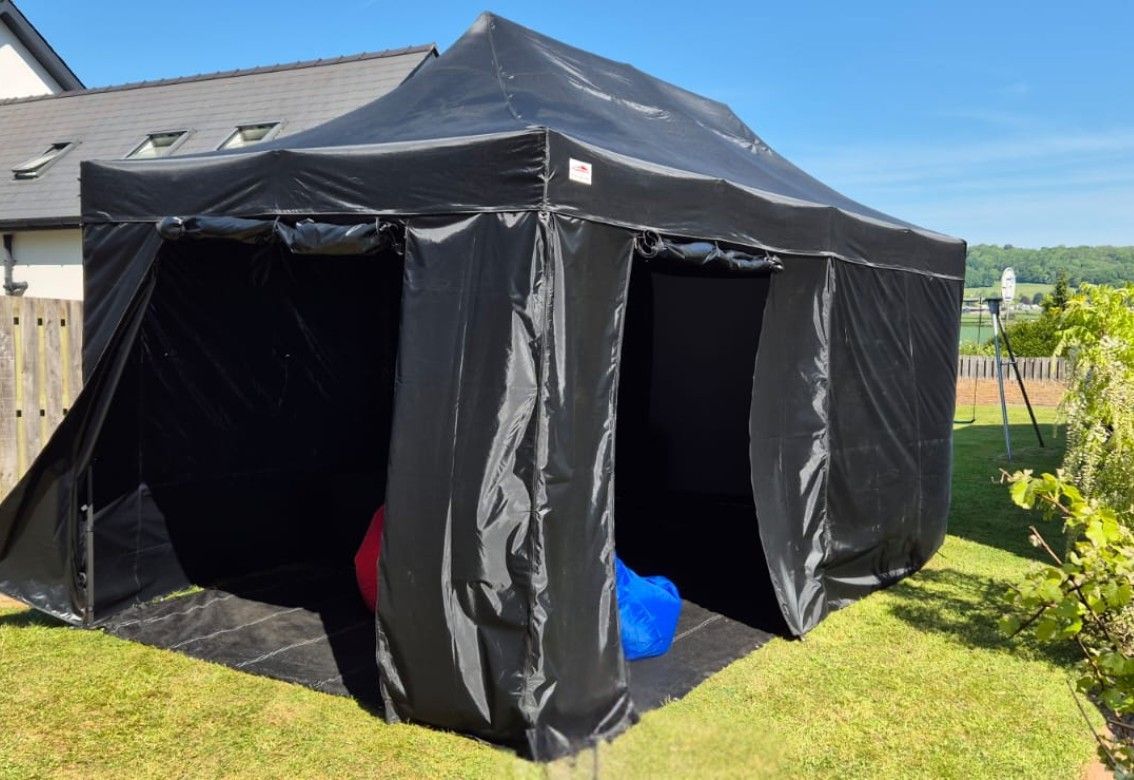 Black pop-up canopy tent with open sides on a grassy yard