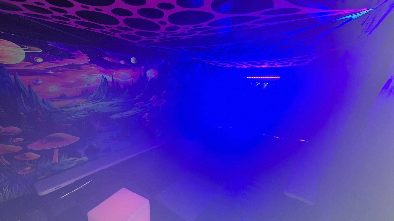 Blue and purple-lit room with abstract wall art and a hazy atmosphere