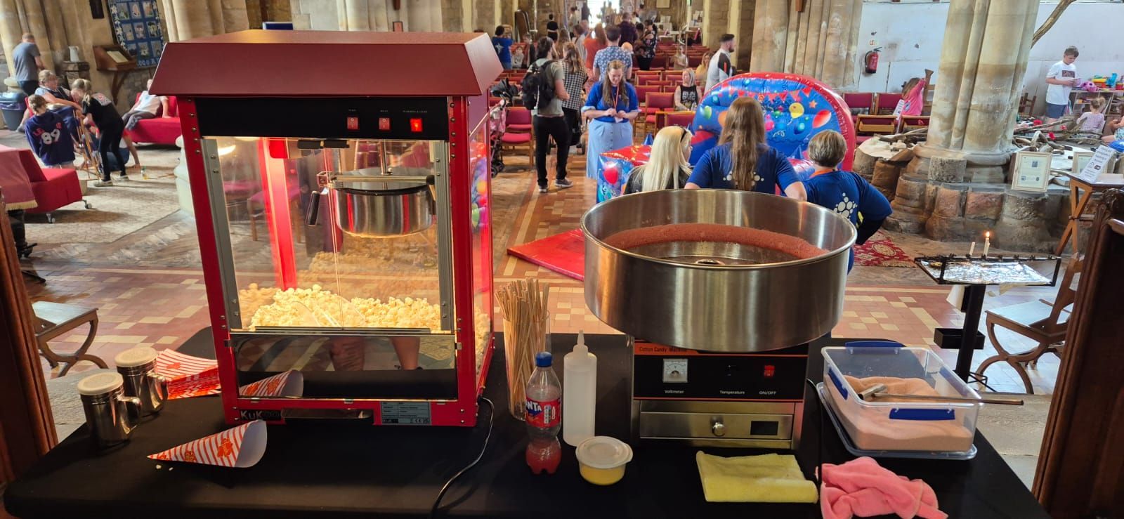 Popcorn machine and serving setup on a counter at a busy indoor event hall
