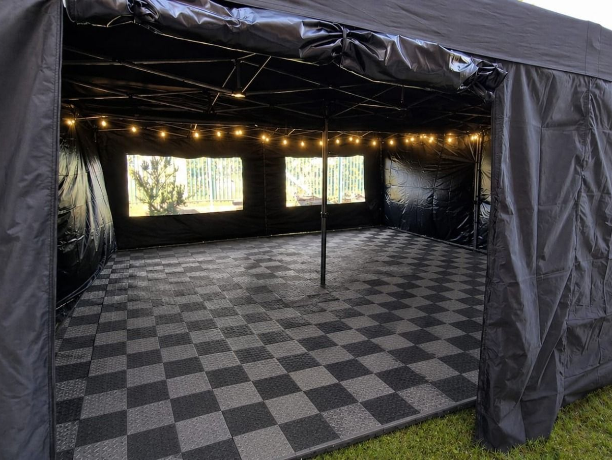 Black pop-up canopy tent with side walls and a matching cover, shown with folded frame parts.