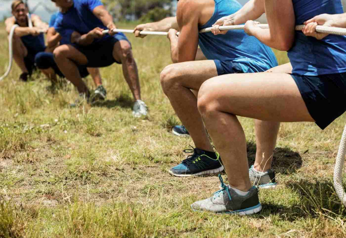 Athletes doing squat jumps on a grassy field, legs bent in a training drill