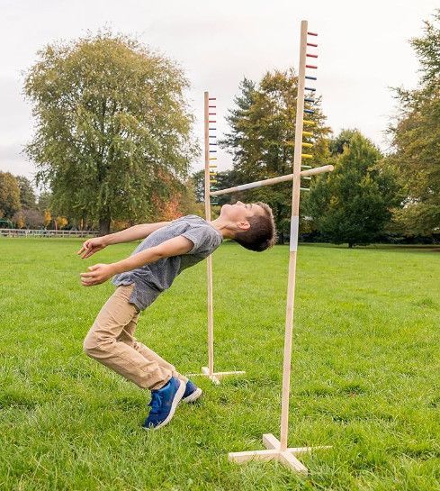 Person arching backward to clear a high jump bar on a grassy field outdoors
