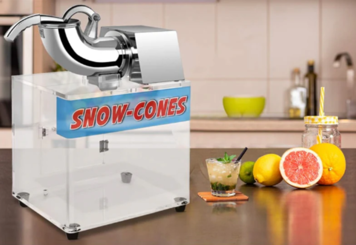 Snow-Cones machine on a kitchen counter with fruit and a drink nearby