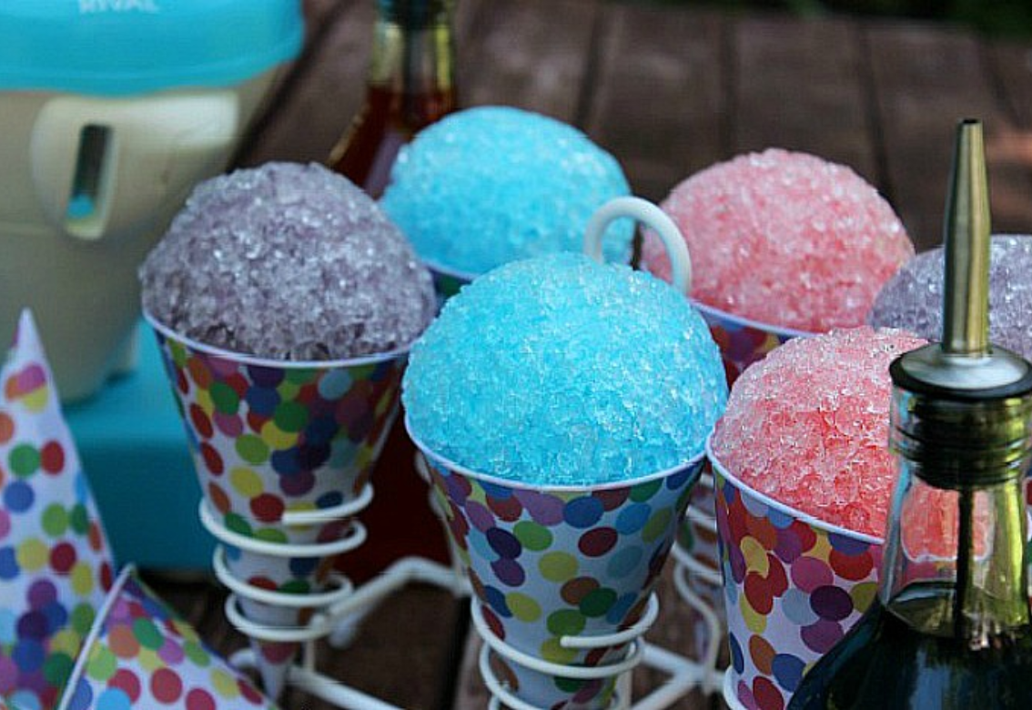 Colorful shaved ice cones in purple, blue, and pink on a tabletop display
