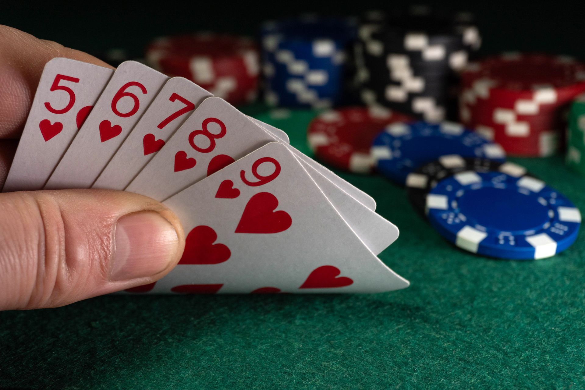 A man holds playing cards with hearts or a straight flush in his hand. A man holds playing cards with hearts or a straight flush in his hand.