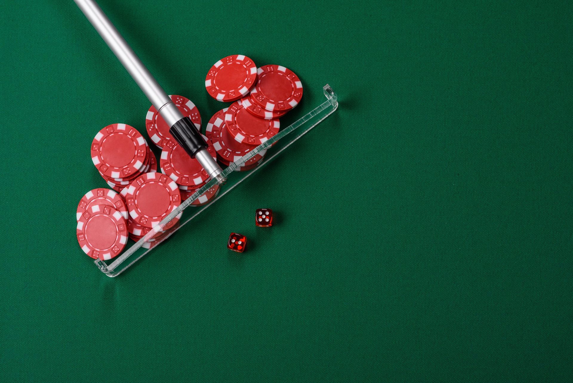 Stack of red poker chips and dice on a green felt table for poker games
