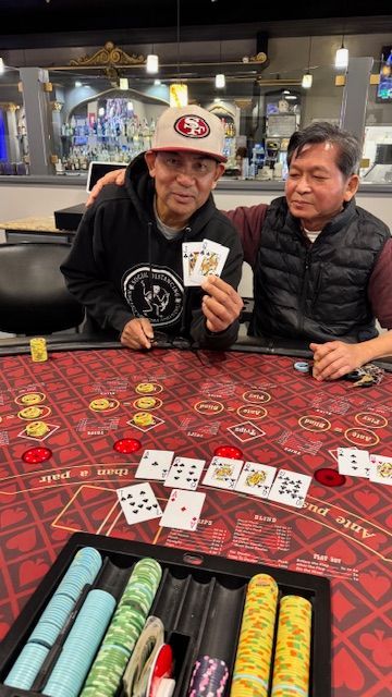 Two men playing poker at a casino table with chips and cards spread out in front of them.