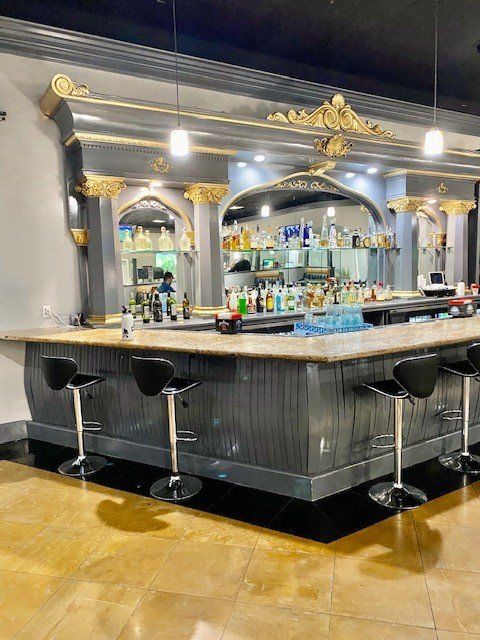 Elegant black-and-gold bar with mirrored shelves, stools, and a glossy countertop in a stylish lounge