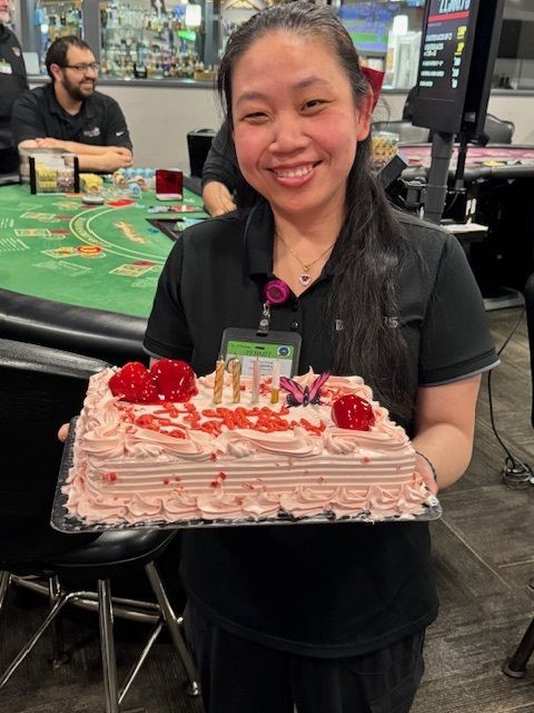 Woman smiling and holding a pink strawberry cake with cherries in a casino setting