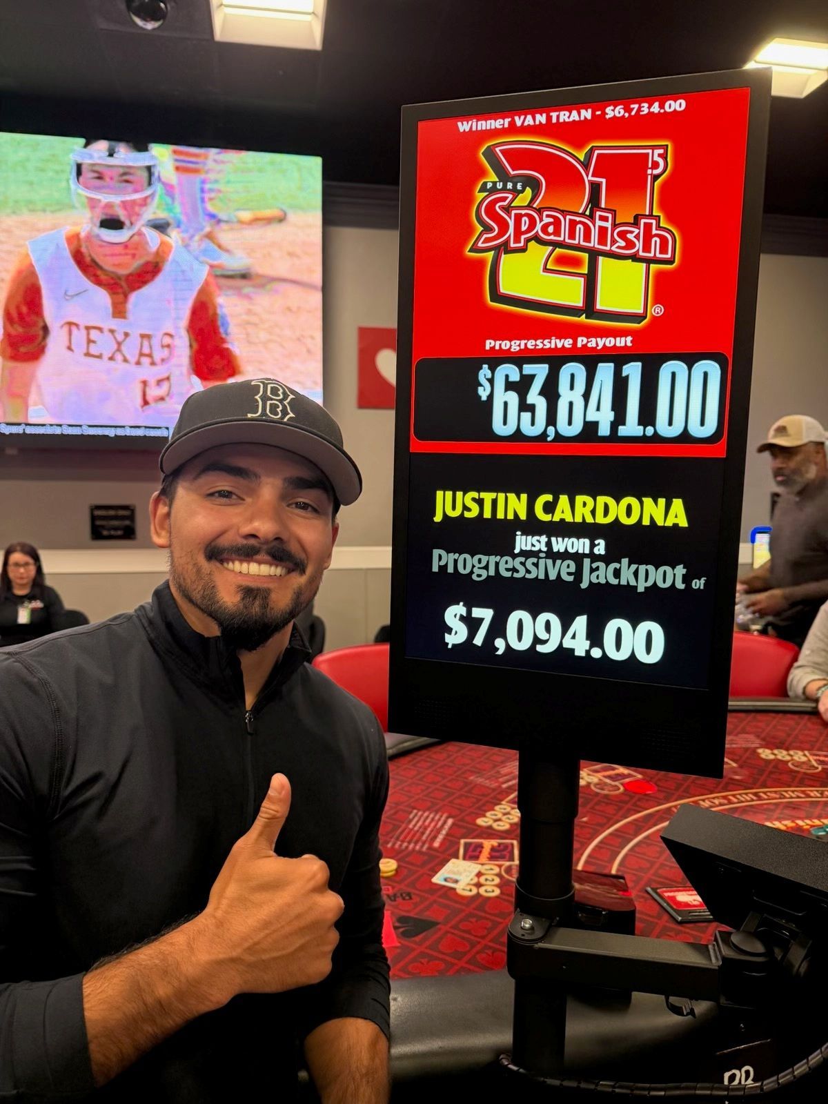 Man posing indoors beside a screen showing a $63,841.00 jackpot and a progressive jackpot sign.