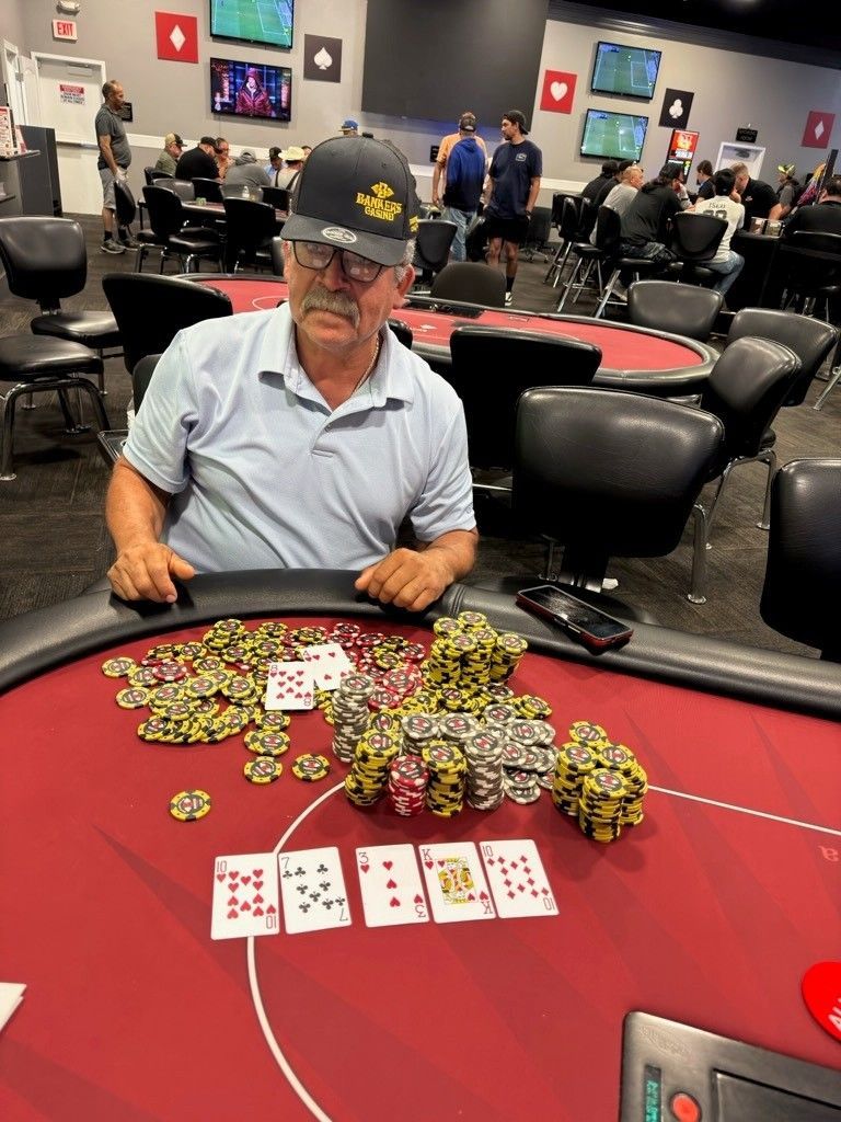 Man at poker table with large stacks of chips and cards in a casino room