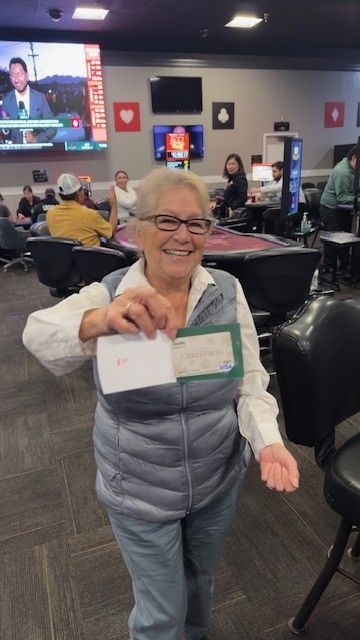 Smiling person in a gray vest holding up a card in a busy indoor hall