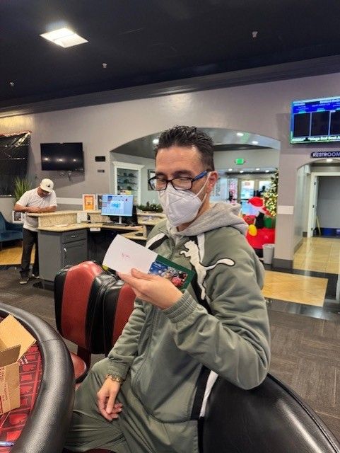Person in glasses and a mask holding papers in a modern indoor lobby or airport terminal.