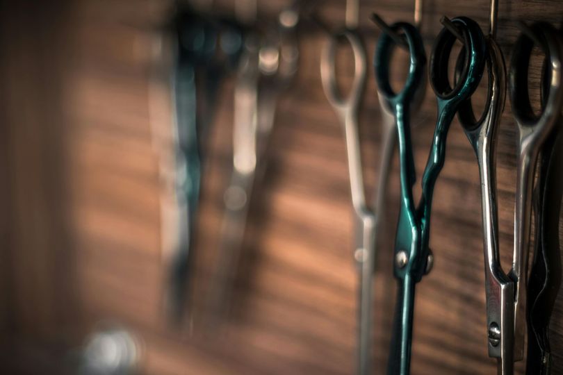 Scissors hanging on a wall rack in a dimly lit barbershop