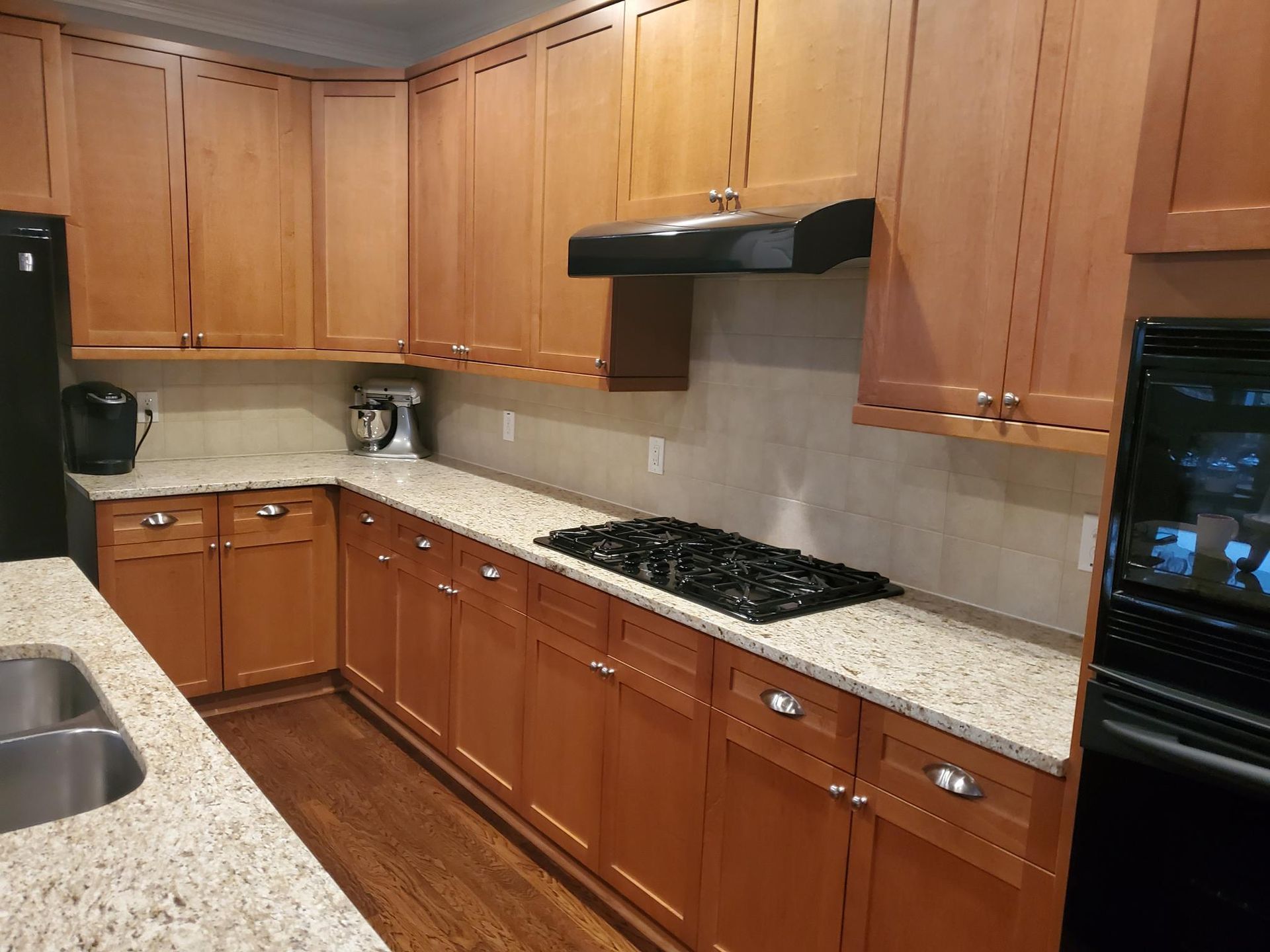 Modern kitchen with wooden cabinets, granite countertops, and a black gas cooktop.