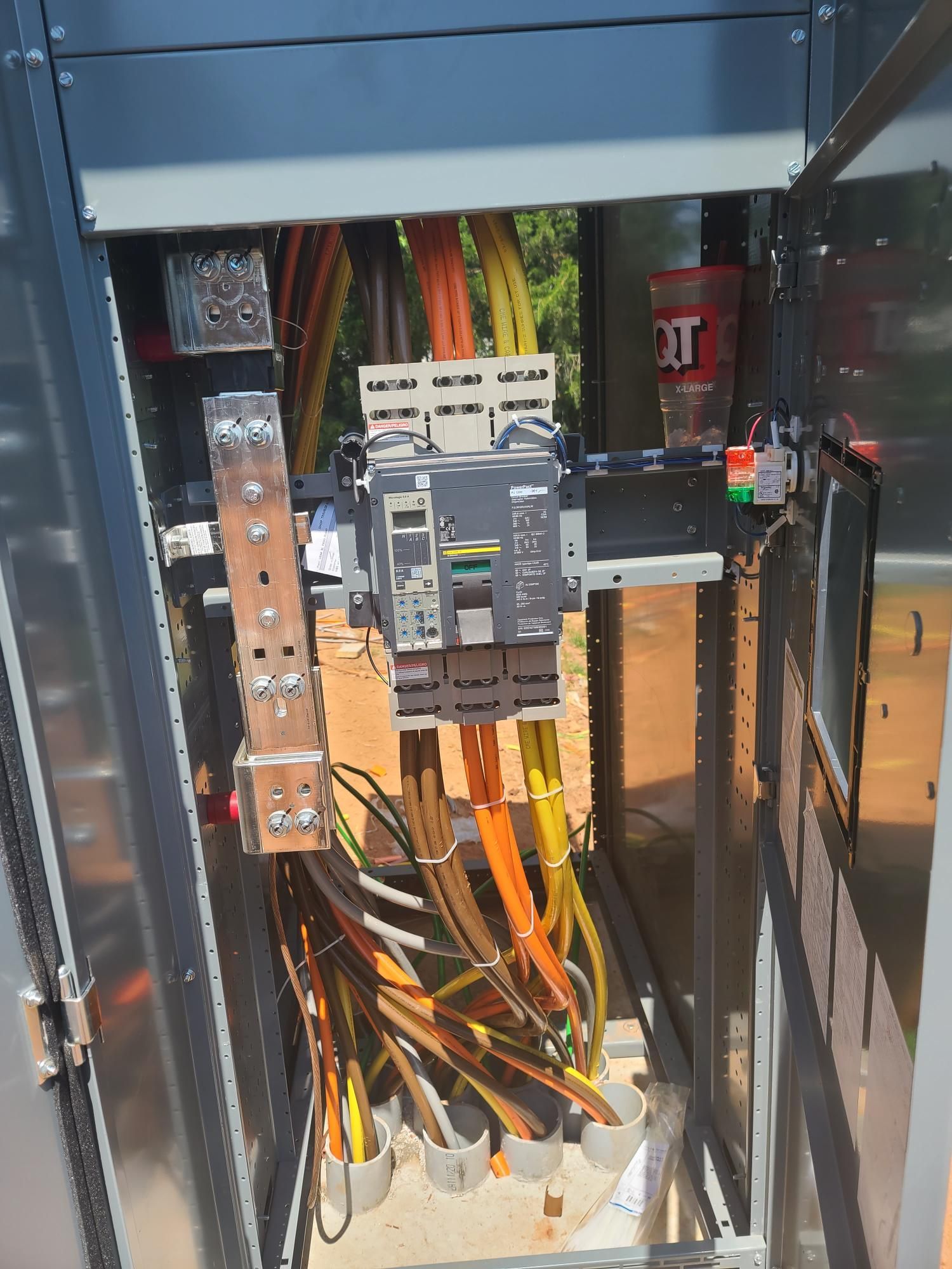 Electrical panel with circuit breakers and bundled wires inside an open cabinet.