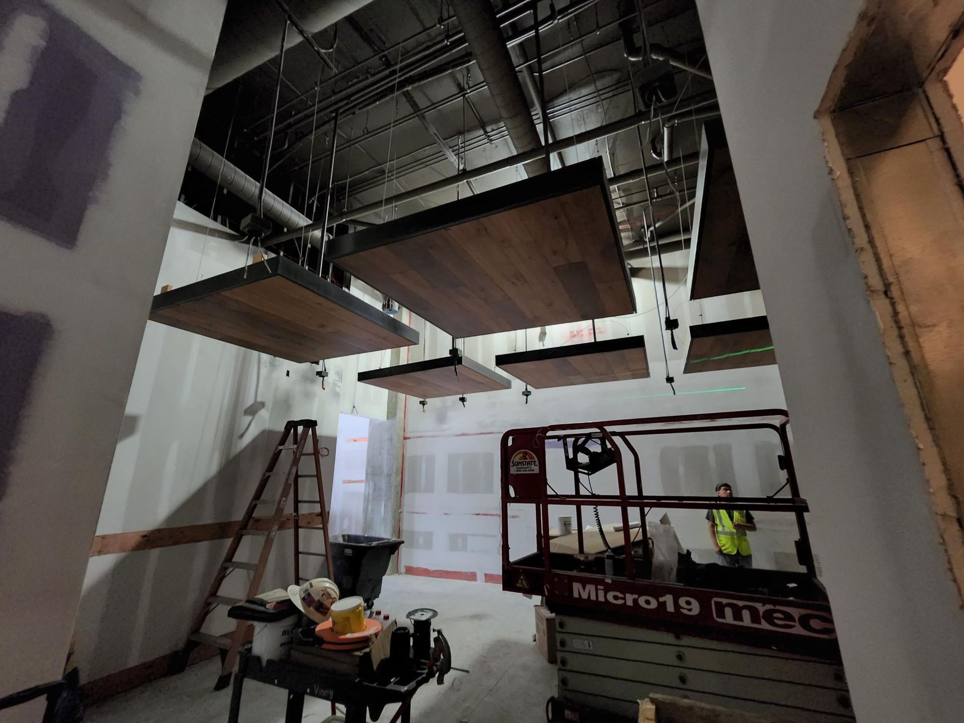 Interior under renovation with exposed ceiling, ladder, tools, and a work platform
