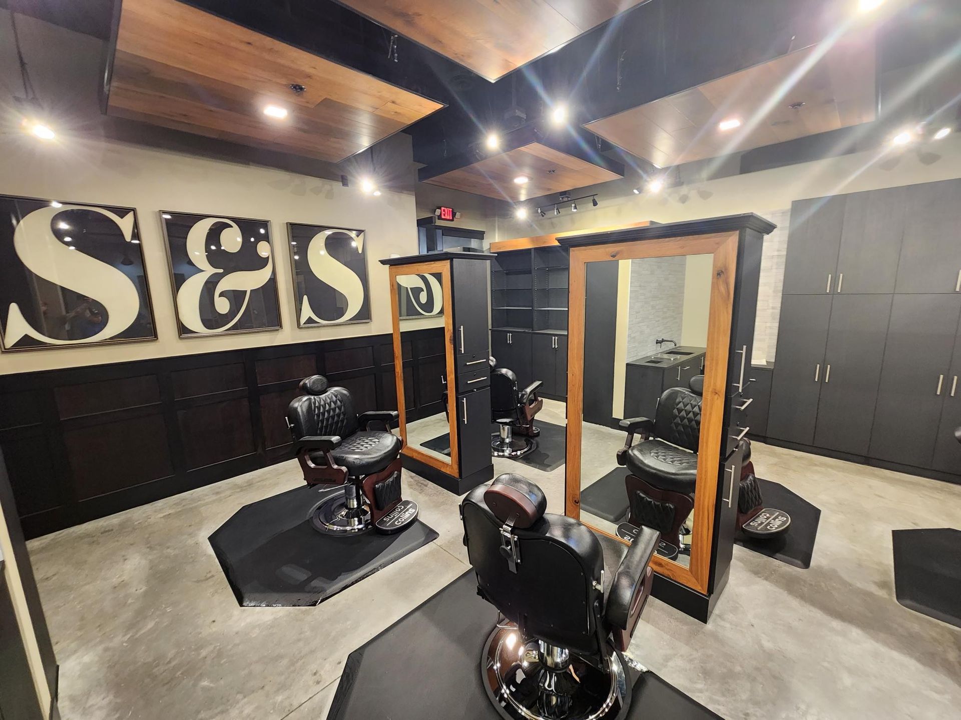 Modern barbershop interior with black chairs, mirrors, and S&S wall sign