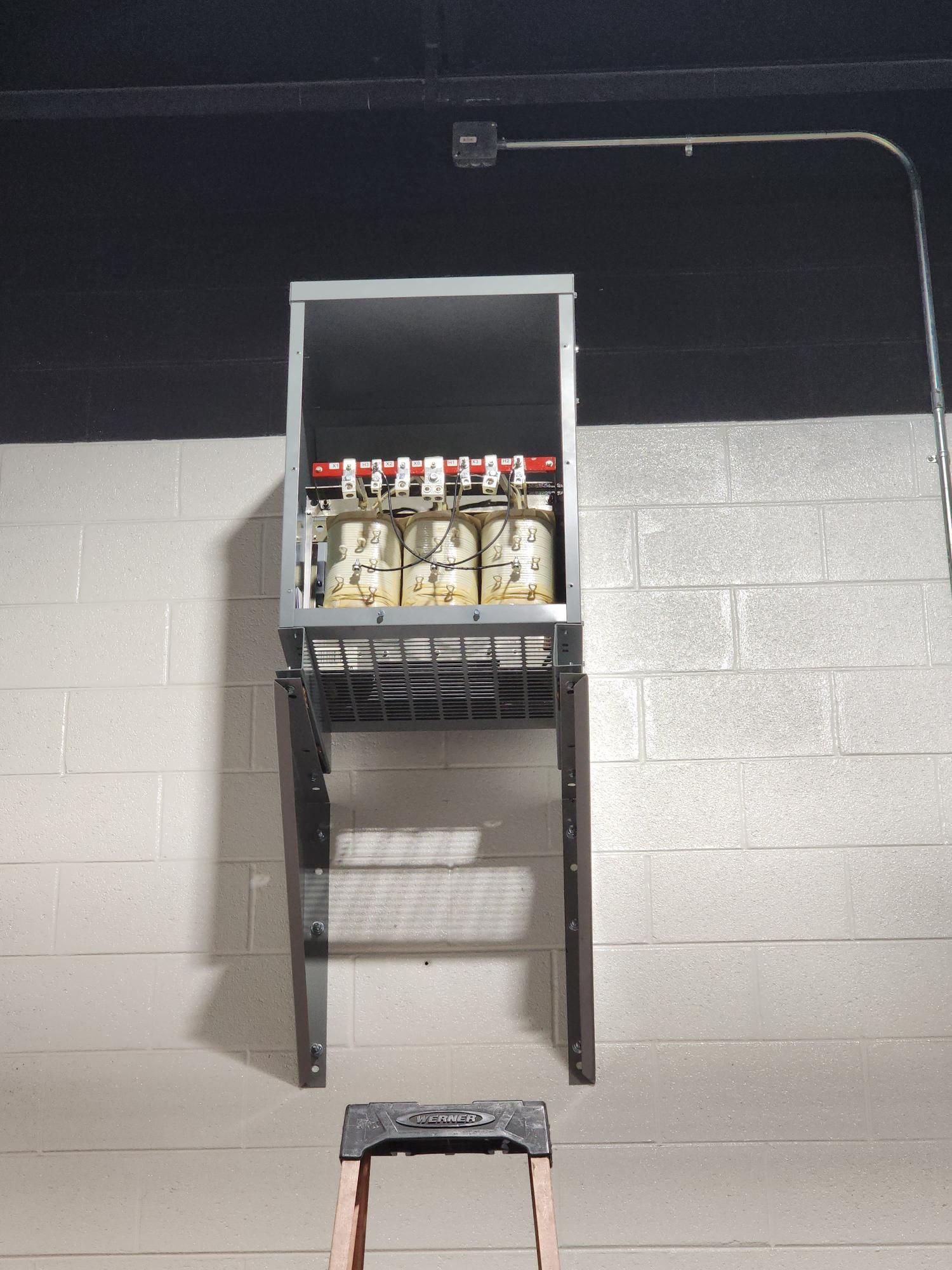 Wall-mounted metal shelf holding several bottles in a gray cinderblock room
