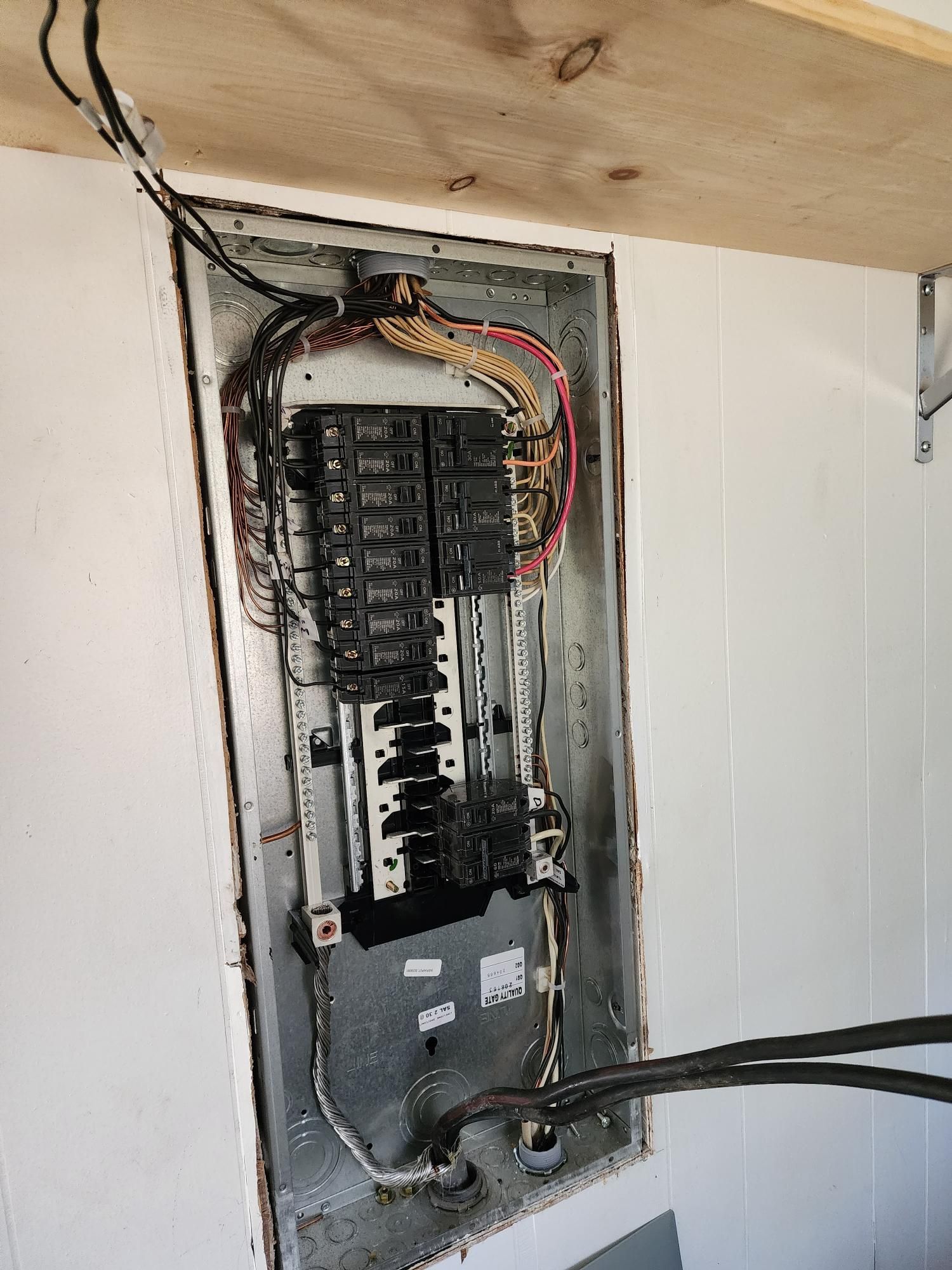 Open electrical breaker panel with exposed wiring in a wall recess