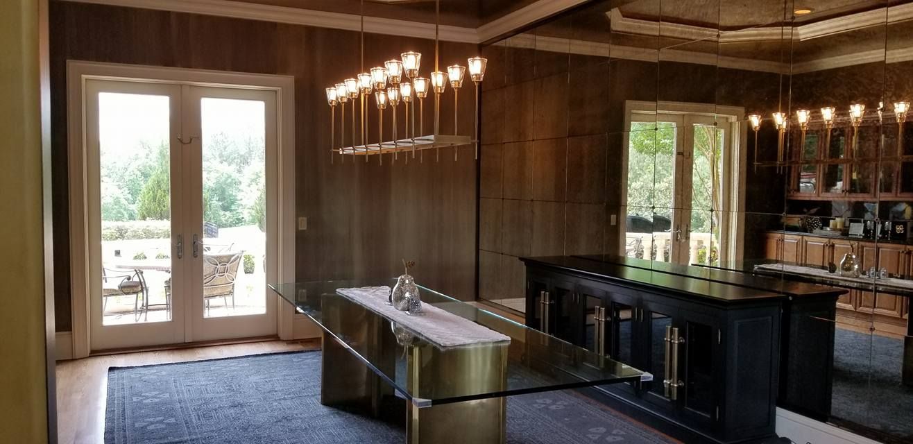 Interior of a dining room with glass table, black bar, and large windows.
