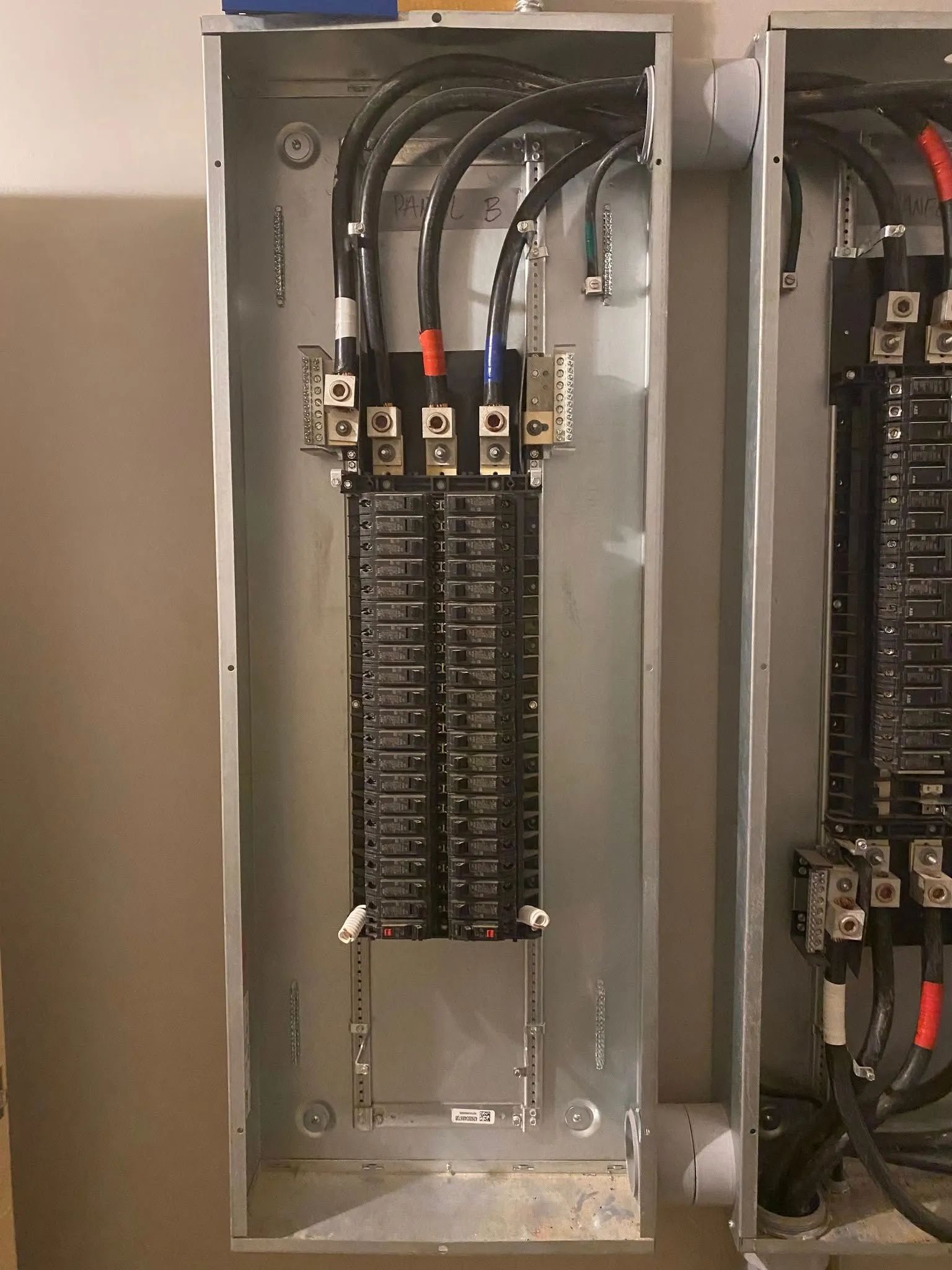 Open electrical breaker panel with rows of black circuit breakers and wiring inside a metal cabinet