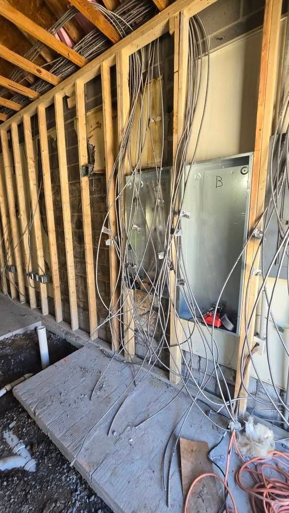 Electrical wiring and panel inside unfinished wall framing.