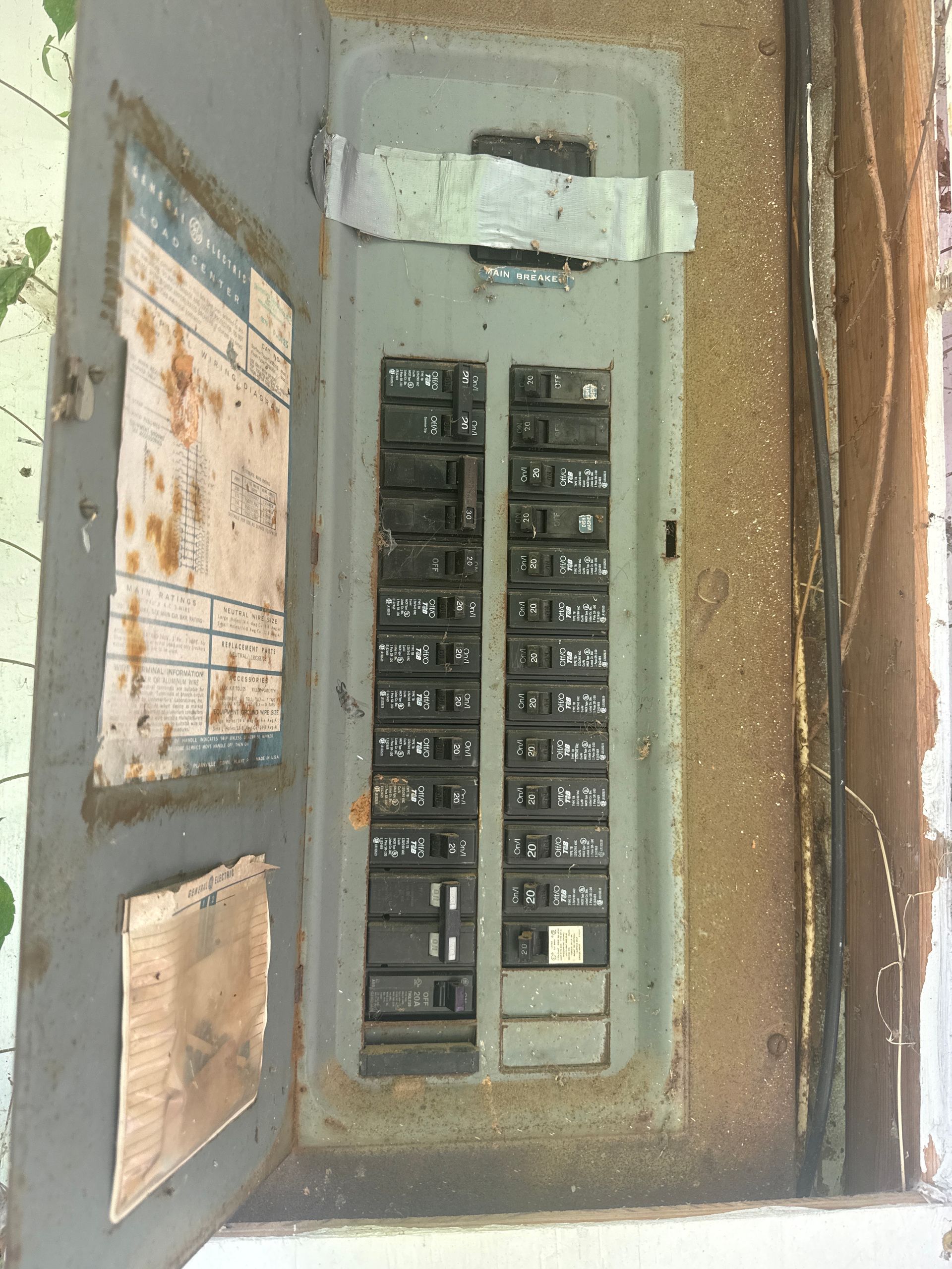 Open electrical breaker panel in a worn wall cabinet with the door ajar