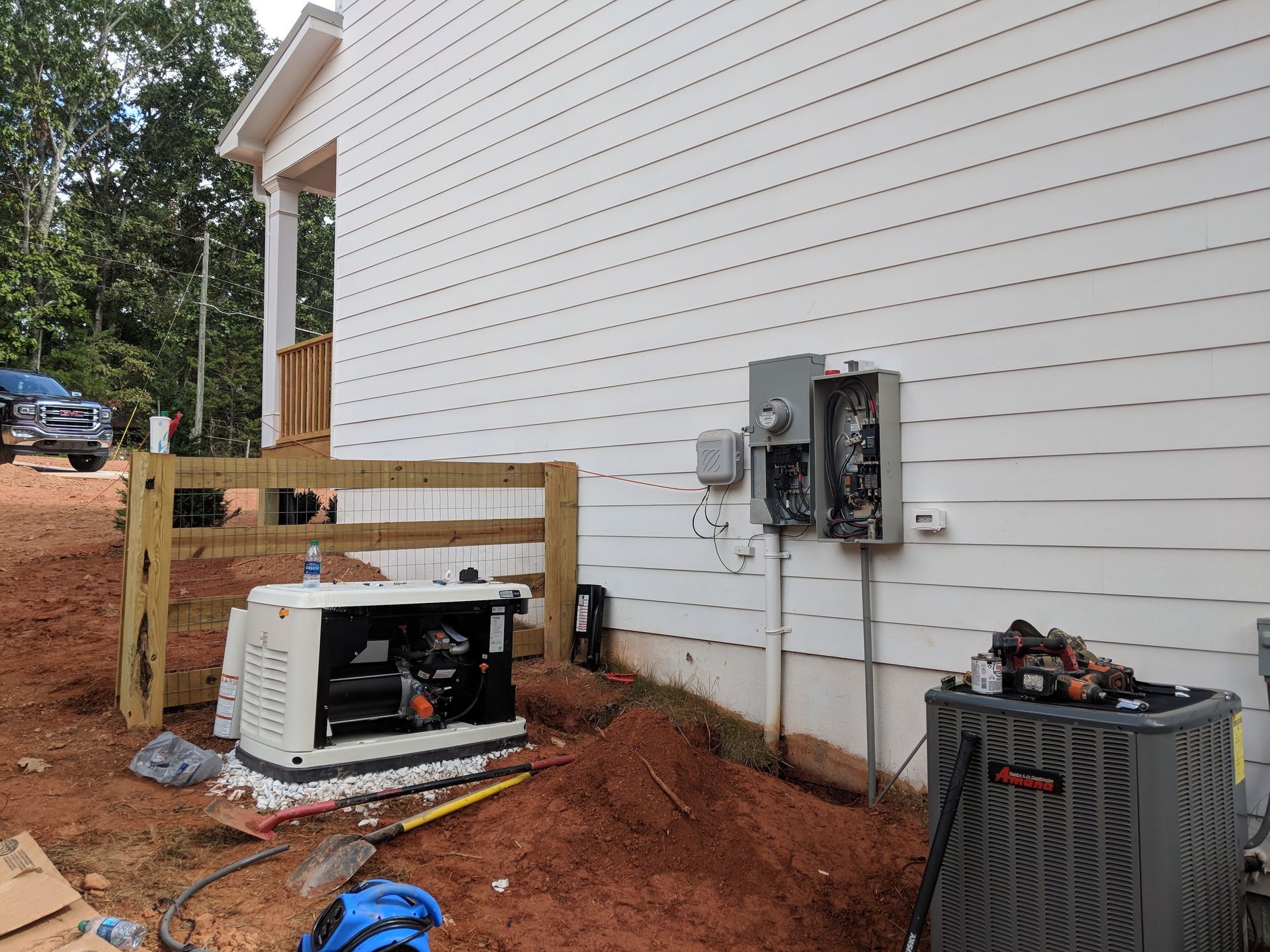 Generator installed next to a house with exposed electrical components and an AC unit.