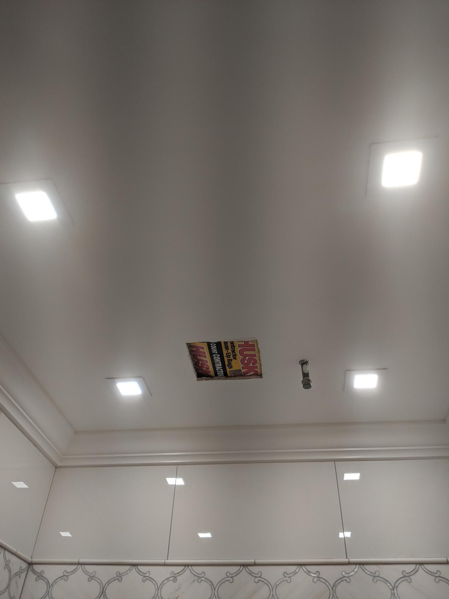 Bright white ceiling with recessed lights and a small colorful panel in the center
